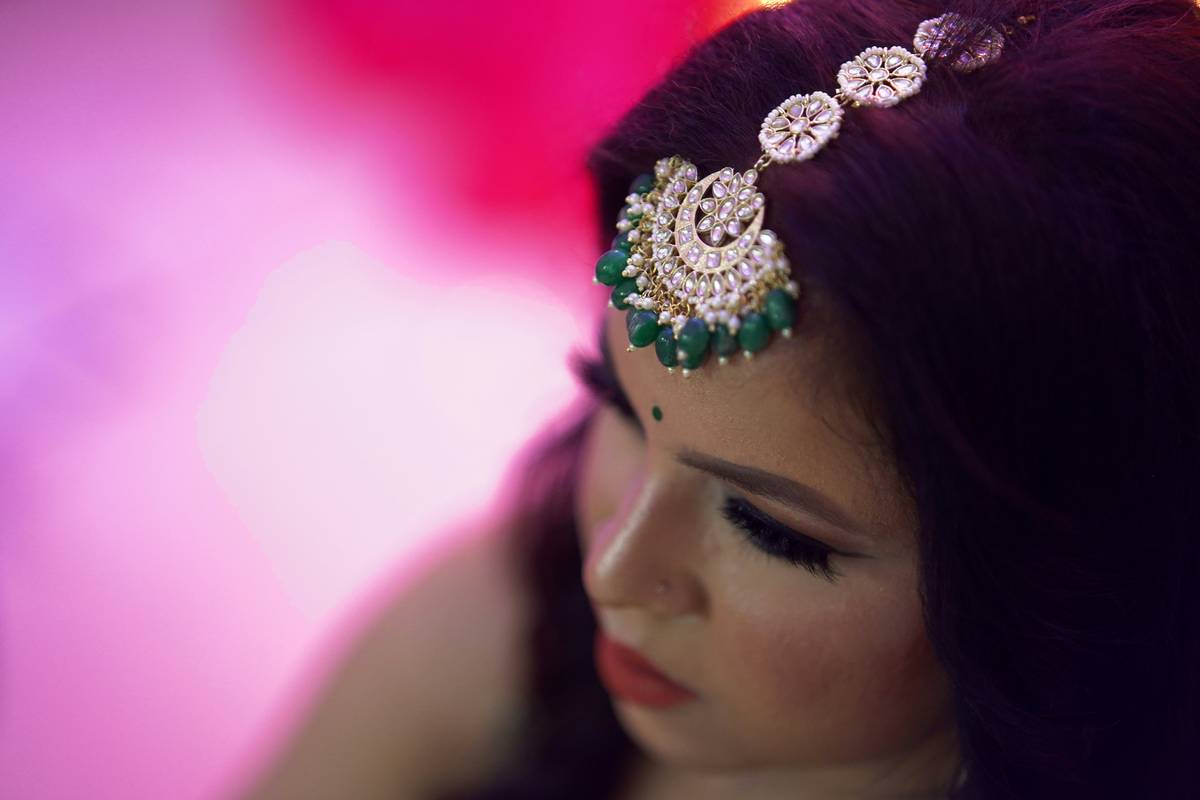 A bride with elegant Hollywood-style waves in her updo holding a bouquet
