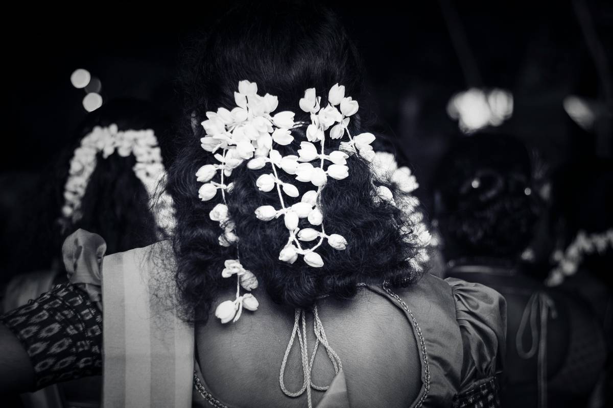 A smiling bride with a classic chignon hairstyle and green hairpins, holding a bouquet.