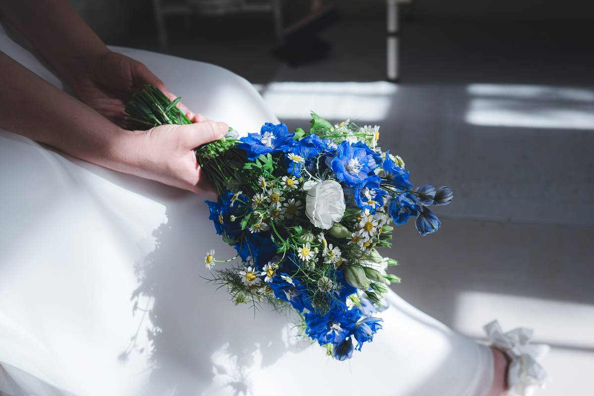 Bride wearing fishtail braid turned into a low bun decorated with baby’s breath flowers.