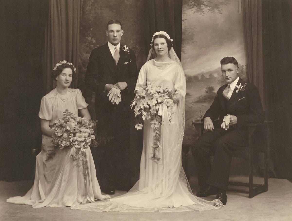 Bride with vintage victory roll hairstyle posing against floral backdrop.