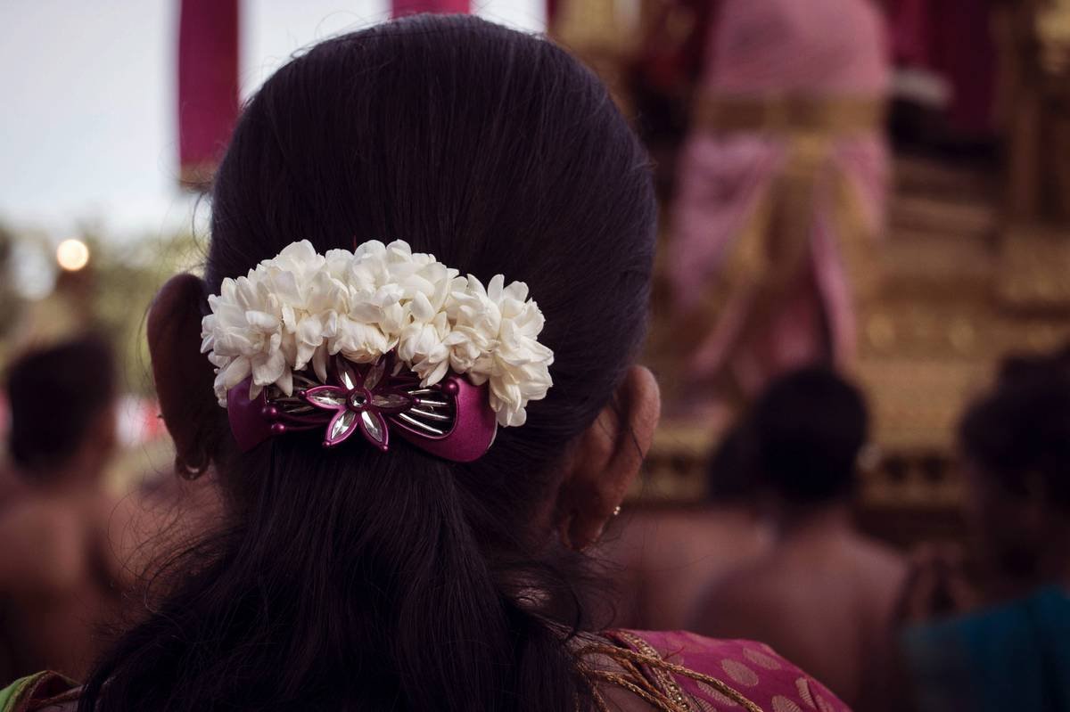 A bride wearing a loose braided crown updo adorned with baby's breath flowers.